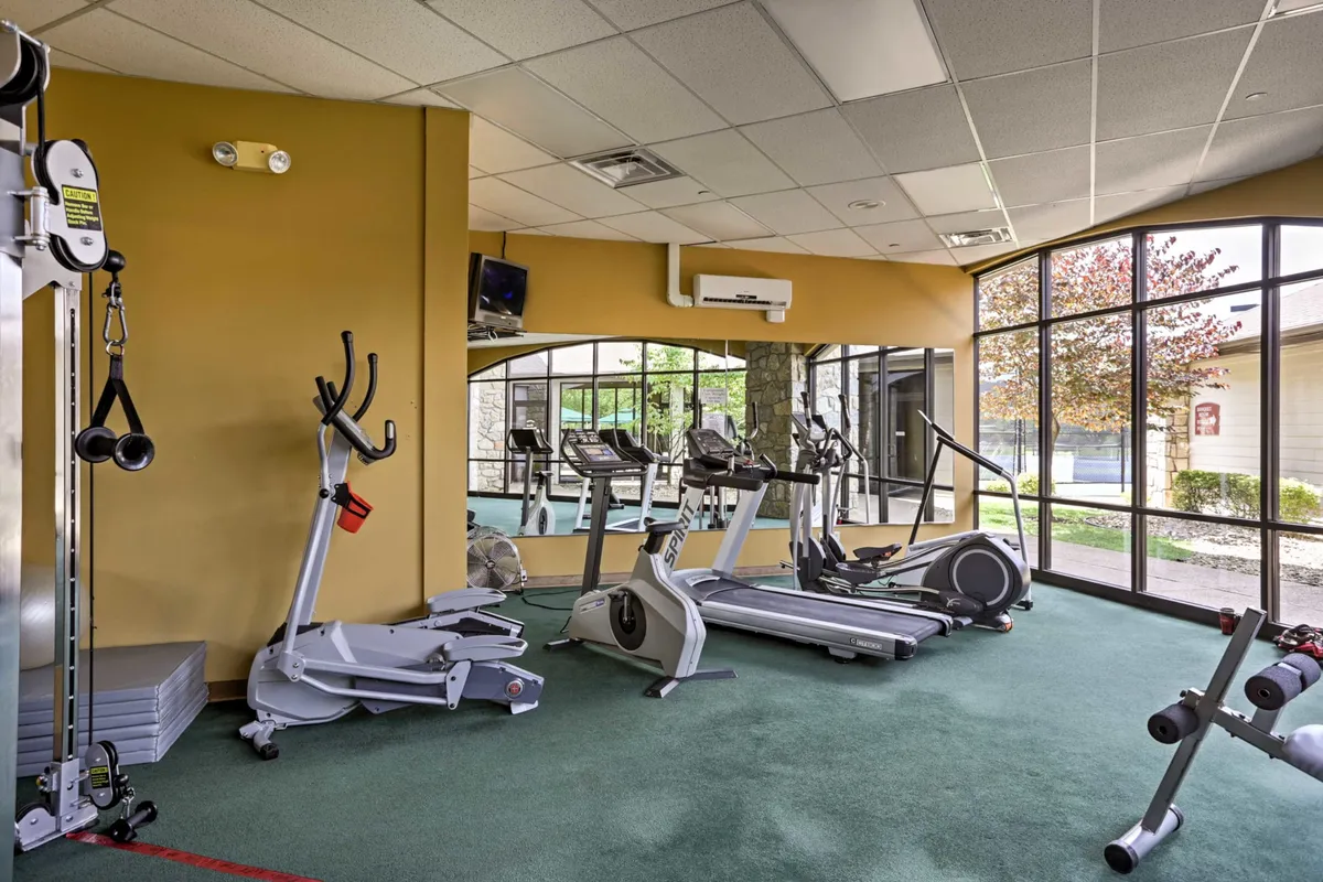 A bright, well-equipped fitness center with treadmills, elliptical machines, and large windows letting in natural light. The atmosphere is energetic and modern, inviting guests to work out or join classes.