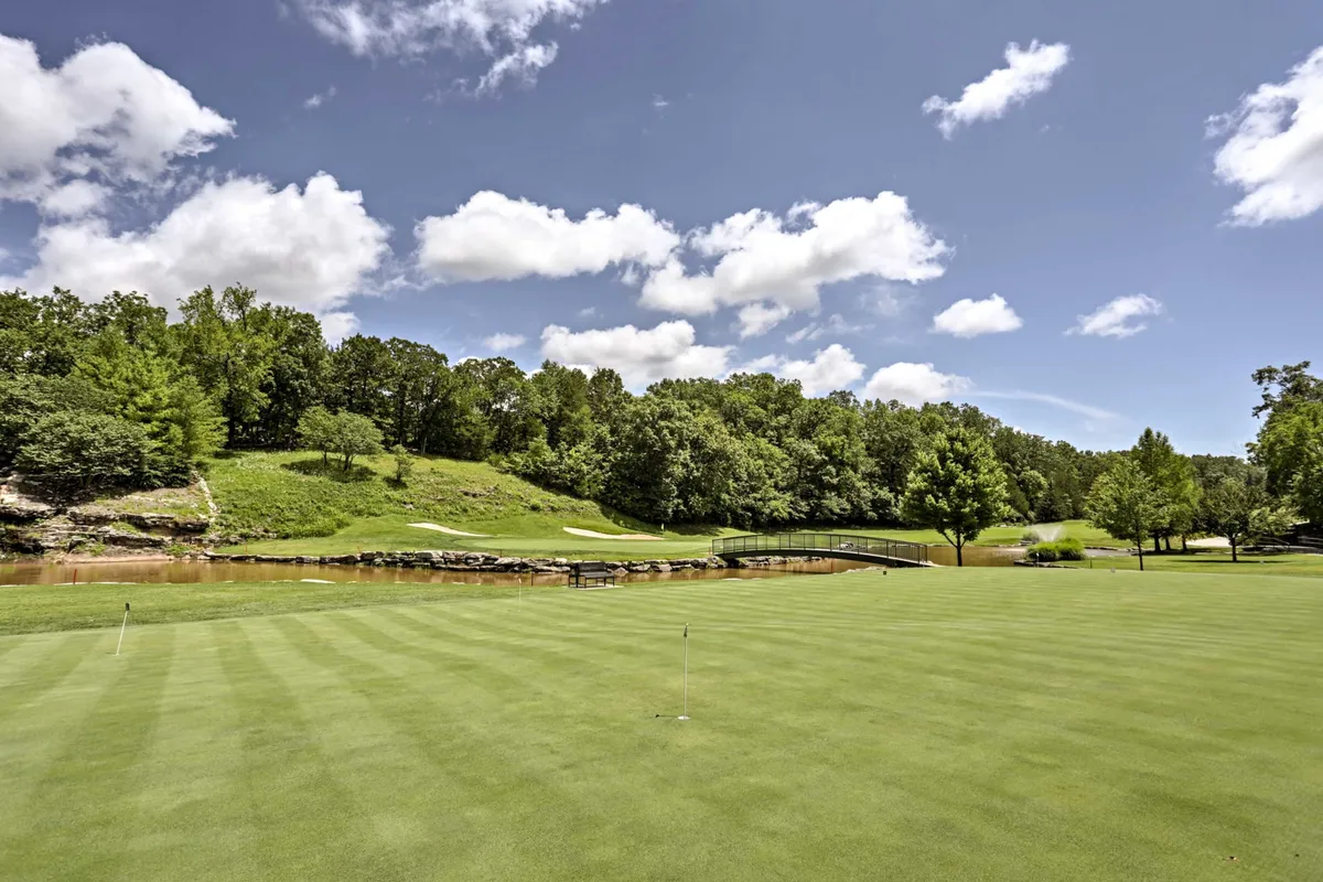 A beautifully maintained golf green with a picturesque bridge, flanked by mature trees and a serene water feature. The setting captures the tranquil, natural charm of the Ledgestone Golf Course, inviting guests to picture themselves teeing off or enjoying a walk in the lush surroundings.